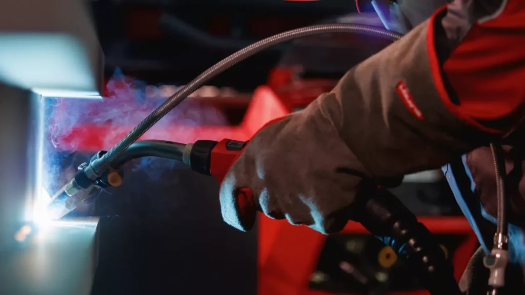 MIG torch with the Velo attachment welding, with a red Fronius TPS/i behind