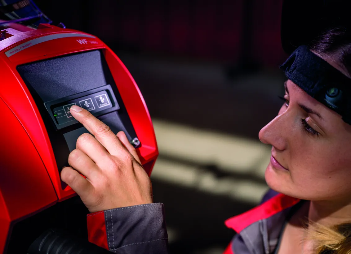 A welder pressing the controls on the WF 25i Velo wire feeder